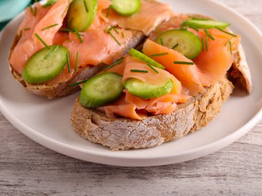 Kahverengi ekmeğin üzerinde salatalıklı füme somon.