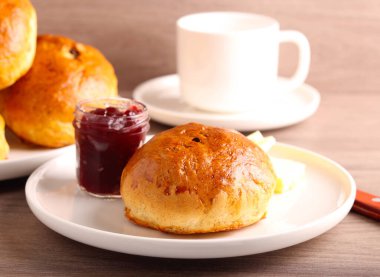 Kuru üzümlü taze çay kekleri, tereyağı ve reçelle servis edilir.