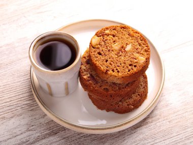 Hurma dilimleri ve fındıklı rulo, tabakta kahve.