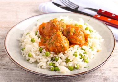 Yeşil bezelyeli pilav üzerine domates soslu köfte.