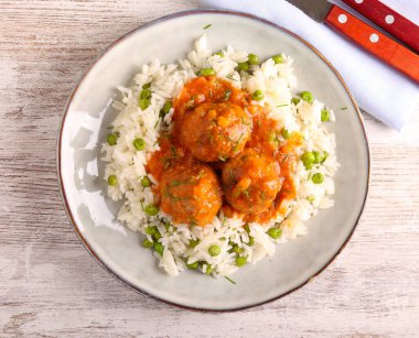 Yeşil bezelyeli pilav üzerine domates soslu köfte.