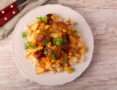 Ananas, mısır ve biberli tatlı ve ekşi köfteler pilav ile servis edilir.