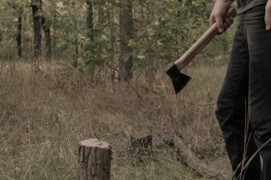 Adamın elinde bir balta var. Fotoğraf bir adamın bacaklarını ve kolunu gösteriyor. Gizemli erkek geçmişi.