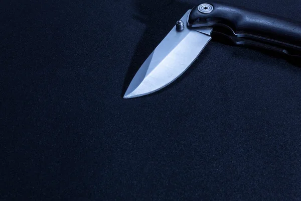 Folding pocket knife with a shiny blade and wooden handle. Smooth dimmed lighting and black background. Top view and close up. I have free space for text or logo.