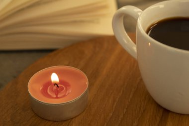 Mum ve bir fincan sıcak kahve yakın plan. Arka planda, kitap açık. Seçici odak.