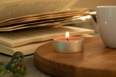 Açık kitap ve mum, seçici odaklanma. Yakın plan. Sabahları güneşin sıcacık gölgeleri.