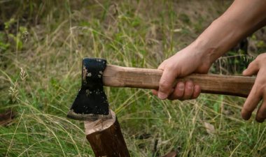 İş yerinde balta kullanmanın bir parçası. Bir adamın eli baltayı tutuyor. Tahta kesme aracı.