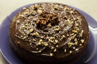 Doğum günü pastası çikolatalı krep serpiştirilmiş ve ceviz serpiştirilmiş. Yukarıdan bak. Tatlı hamur işleri. Tabakta kahverengi turta.