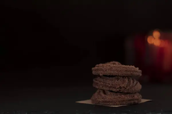 Cookie rings with cocoa and cinnamon on a black background. Aesthetics of homemade sweet pastries. Selective focus. Free space for text.