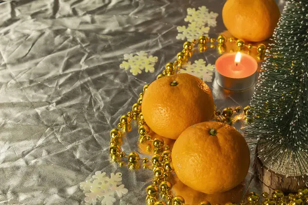 Items and fruits that create a warm New Year\'s atmosphere. Tangerines, a candle and a small Christmas tree are symbols of the New Year.