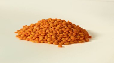 Beyaz arka planda kırmızı mercimek yığını, izole edilmiş. Doğu mutfağının küçük baharatlı taneleri. Pişirmek için çiğ yemek. Ön manzara. Sağlıklı ve vitamin açısından zengin..