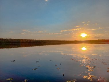 Ayna nehri ve mavi gökyüzü. Akşamları yaz manzarası. Gün batımı. Nehrin yüzeyinde güneşin ve gökyüzünün yansıması..