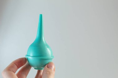 Beyaz arka planda bir insanın elinde şırınga (lavman için ampul) bulunur. Temizlik için tıbbi endüstri ögesi.