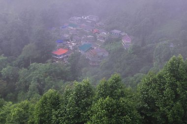 Puslu ve bulutlu dağ köyünün panoramik manzarası muson mevsiminde yeşil ormanlarla çevrili, Hindistan 'ın batısındaki Darjeeling Hill istasyonu yakınlarında.