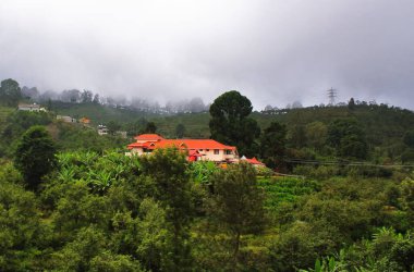 Yağmur mevsiminde yemyeşil tahtırevanlar üzerinde muson bulutları, Tamilnadu, Güney Hindistan 'daki Kodaikanal Tepesi yakınlarındaki dağ köyü.
