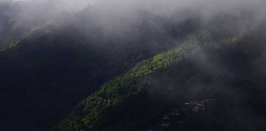 Hindistan 'da Darjeeling yakınlarındaki himalaya eteklerinde, muson mevsiminde bulutlu ve sisli yemyeşil Himalaya dağ köyünün panoramik manzarası