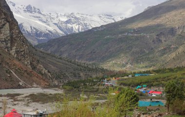 Manzaralı Jispa köyü, karla kaplı himalaya dağları ve Hindistan 'ın Himachal Pradesh kentindeki Lahaul bölgesindeki yemyeşil Bhaga Nehri vadisi.