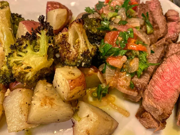 seared beef steak, baked potatoes and vegetable salad -image