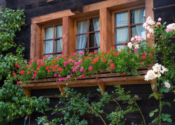 Window of a wooden house with flowers in the garden