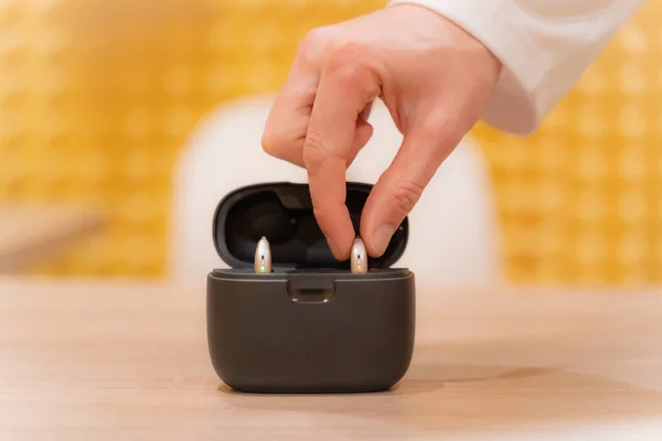 Hand of an audiologist doctor placing a hearing aid in its case