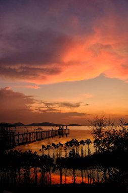 Günbatımının altın renkleri gökyüzünü boyar ve sakin suları yansıtır. İskelenin yanında huzurlu ve resimsel bir manzara yaratır.