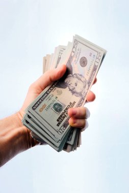 Beyaz bir arka planda bir yığın doları tutan bir adam..