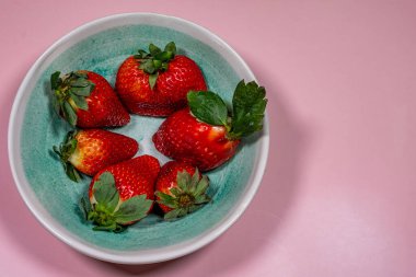A Refreshing Treat: Fresh Strawberries on a Bold pink Table