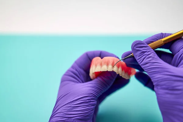 Diş teknisyeni yeşil bir tezgahta çıkarılabilir takma diş yapıyor.