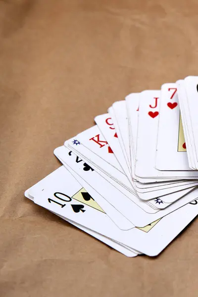Shuffling of poker cards spread out on a cardboard-like surface.