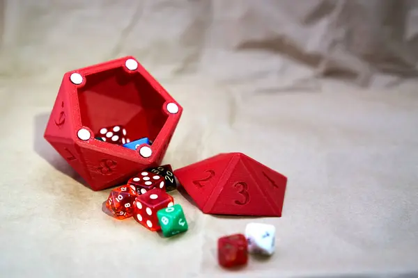 Çeşitli boyutlarda ve renklerde zarlar, karton benzeri bir yüzey üzerinde kırmızı zar şeklinde zarlar var..