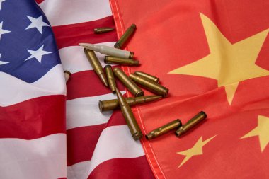 Amerikan ve Çin bayrakları. Tüfek mermileri etrafa saçılmış, bayraklar biraz kırışmış..
