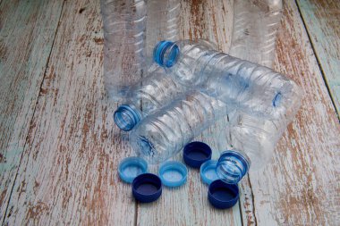 Geri dönüşüm için ahşap bir masaya yerleştirilmiş kapalı ve açık plastik şişelerin genel görünümü.