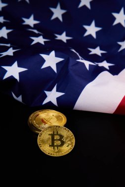 Amerikan bayrağının önüne dijital ekonomi ve ABD teknolojik gelişmeleri sembolize eden iki bitcoin yerleştirildi.