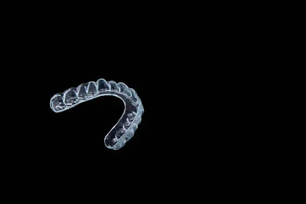 Açık bir ağız koruyucusu koyu siyah bir arkaplana yerleştirilmiş, makro fotoğrafçılığa uygun, karmaşık detaylarını ve benzersiz tasarımını vurgulamak için.