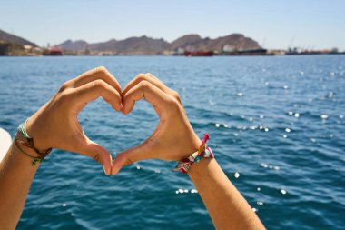 Denizin ortasında bir kadının elleriyle oluşturulmuş bir kalp..