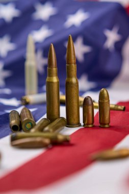 Amerikan bayrağının tepesinde yıldız ve şeritlerle sıralanmış farklı büyüklükteki fişekler ve mermiler.