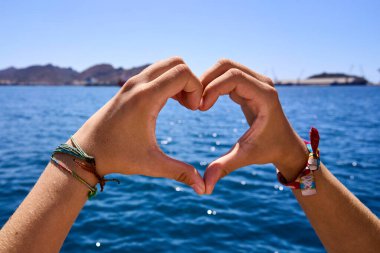 Denizin ortasında bir kadının elleriyle oluşturulmuş bir kalp..