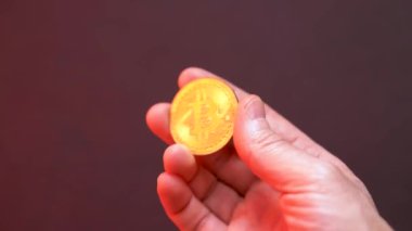 Mans el kırmızı ışıkta altın bir bitcoin gösteriyor.