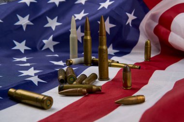 Amerikan bayrağının tepesinde yıldız ve şeritlerle sıralanmış farklı büyüklükteki fişekler ve mermiler.