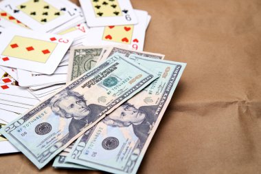 Poker kartları ve dolarlar karton gibi bir yüzey üzerinde yatıyor..