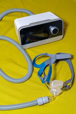 Sarı bir yüzey üzerinde Uykucu Apne CPAP Makinesinin tüp ve maskesi.