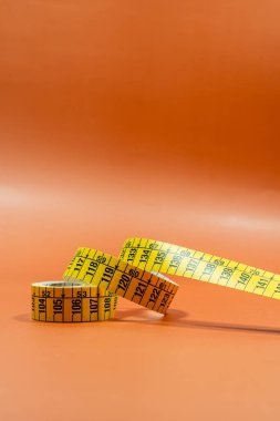 Turuncu zemin üzerinde parlak ışık altında dikiş bandı terziliğinin üzerinden