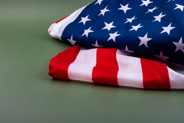 Amerikan bayrağı düzgün bir şekilde yeşil bir zemine katlanır. Vatanseverlik gösterisine derinlik katan gölgeler bırakır..