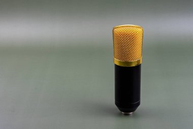 Altın ızgaralı mikrofon, gri bir arka planda, bir stüdyo ortamında, temiz ve çıtır çıtır ses kaydı için kullanılmaya hazır..