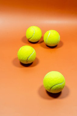 Turuncu bir yüzeyde parlak sarı tenis topları yığını.