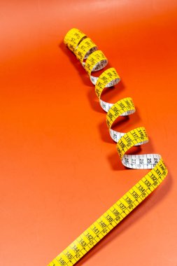 Turuncu zemin üzerinde parlak ışık altında dikiş bandı terziliğinin üzerinden