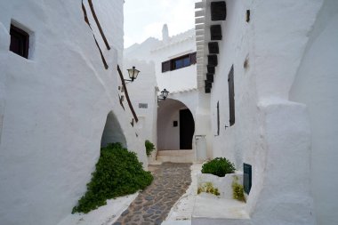 Binibeca, Menorca 'da dar bir caddenin aşağısında beyaz binalar ve kaldırım taşından yollar olan bir manzara köyün eşsiz mimarisini gözler önüne seriyor..