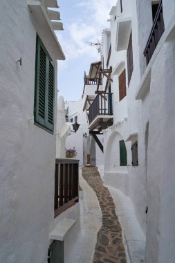 Binibeca, Menorca 'da beyaz binalar ve taş bir yolun yer aldığı dar bir caddenin manzarası..