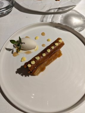 Çok güzel bir tabakta, güzel bir akşam yemeği için mükemmel beyaz bir tabakta, dondurmalı pasta ve süslemeli börek bulunur..