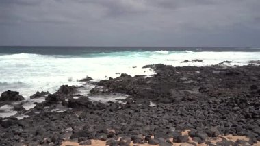 La Graciosa, Lanzarote 'deki dramatik kıyı manzarası, engebeli bir kıyı şeridi, dalgalar ve karamsar bir gökyüzü. Sahne saf güzelliği yakalar..